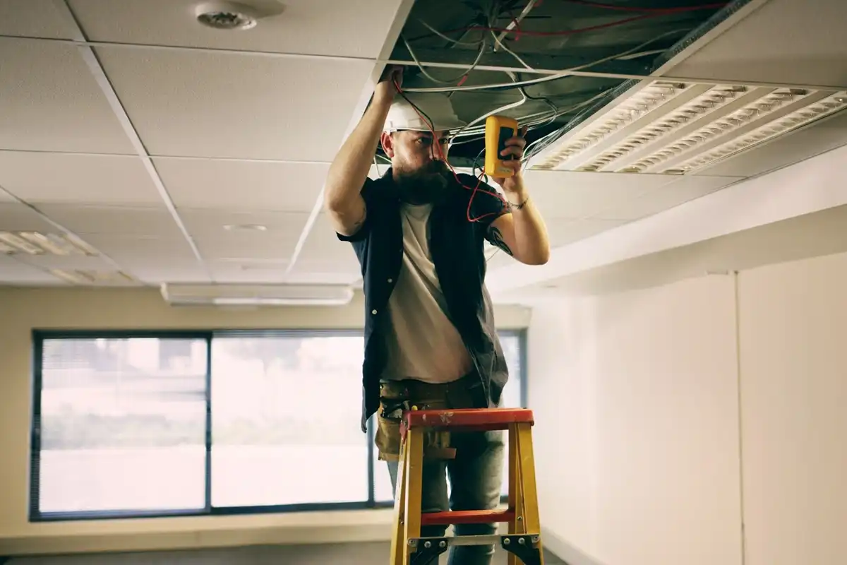 elektryk sprawdzający instalację elektryczną w biurze